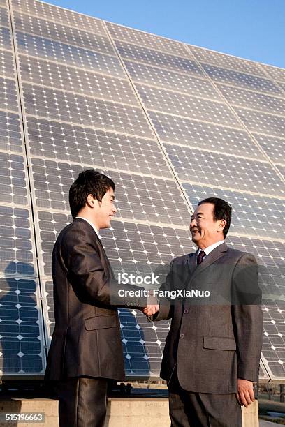 Shaking Hands In Front Of Solar Panels Stock Photo - Download Image Now - Honesty, Responsibility, Asian and Indian Ethnicities