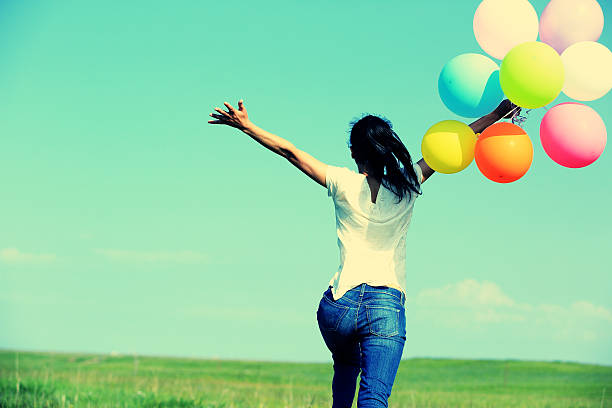 young asian woman  on green grassland with colored balloons