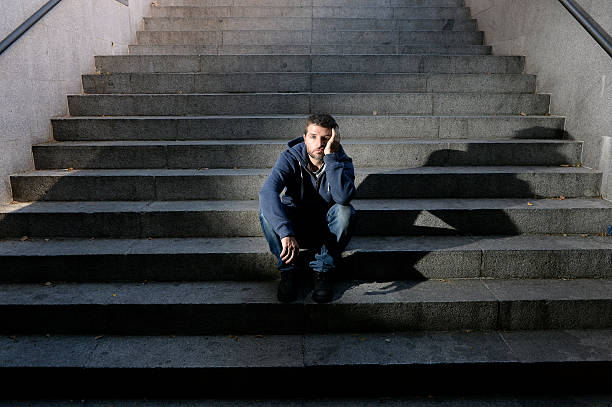 istock Young man suffering depression sitting on ground street concrete stairs 515196907
