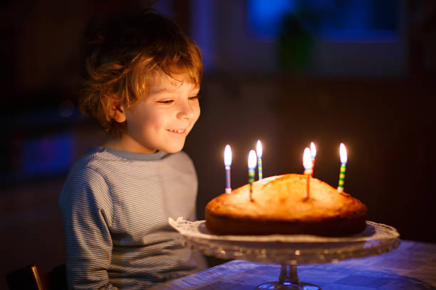 istock Little kid boy blowing candles on birthday cake 515199266