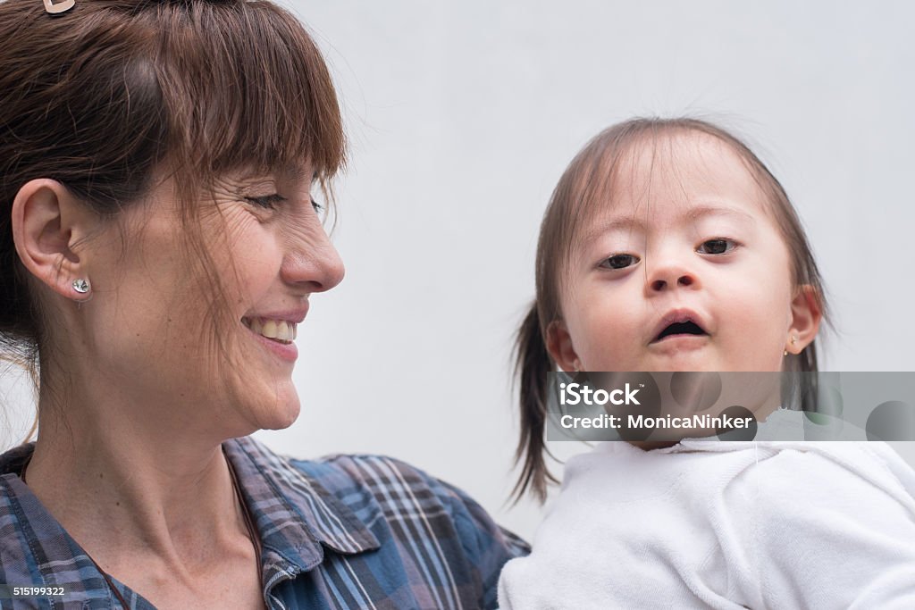 Special caring Mature woman carrying her little girl with down syndrome 2-3 Years Stock Photo