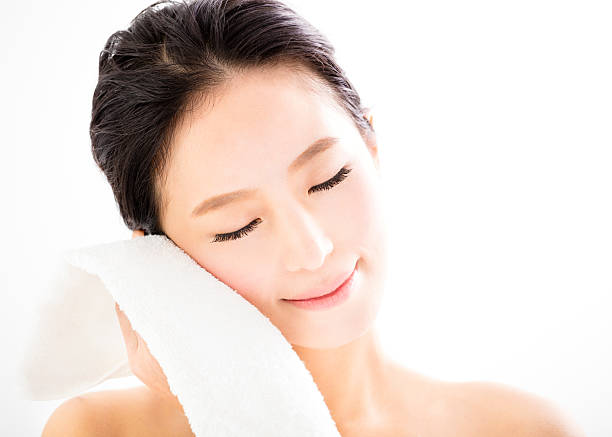 young woman cleaning her face with  towel