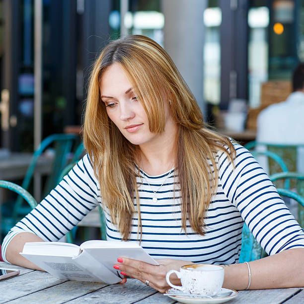 istock Woman drinking coffee and reading book in cafe 515201574