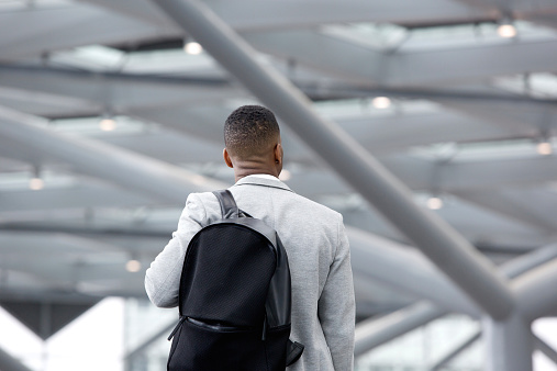 Rear view portrait of a black man standing in airport with bag