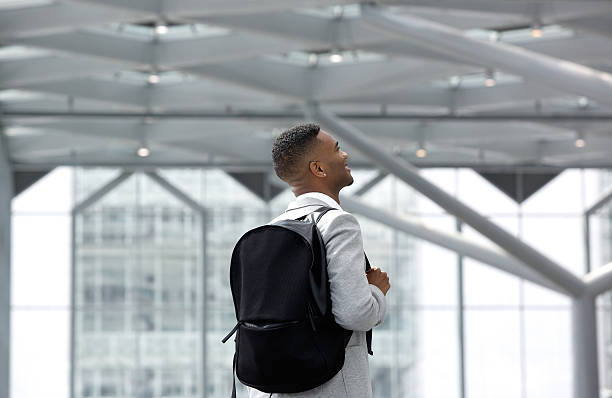 молодой человек улыбается с сумки в аэропорт - men african descent looking up smart casual стоковые фото и изображения