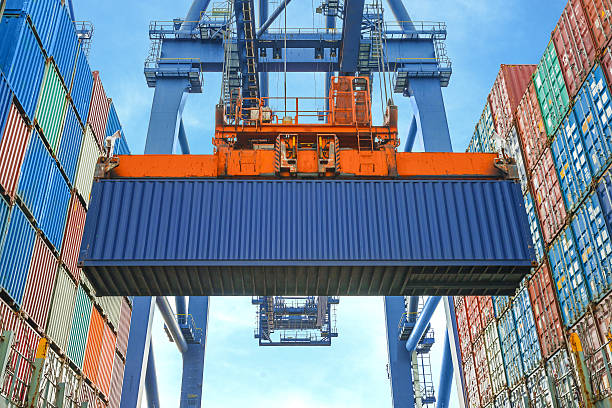 shore crane loading containers in freight ship - container ship stockfoto's en -beelden
