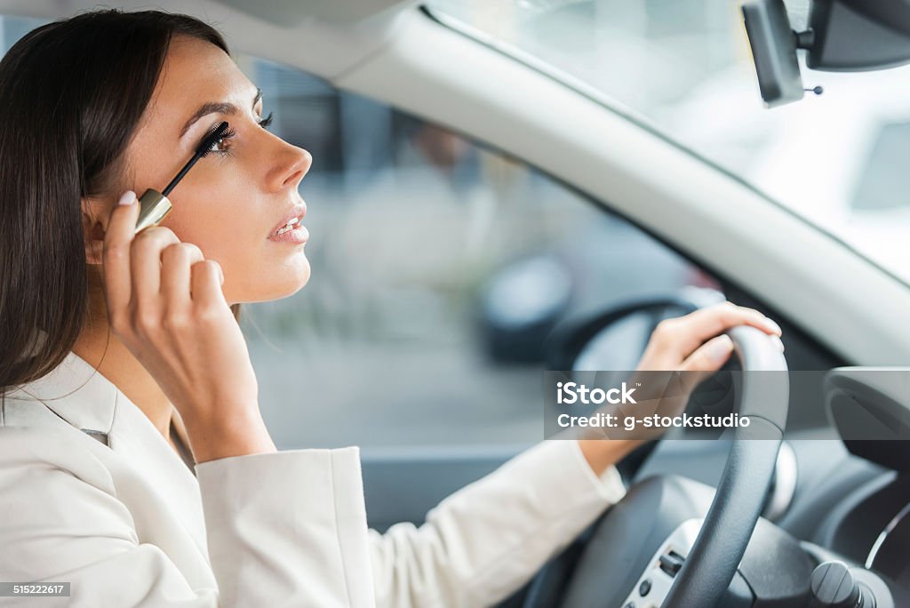 Careless driver. Side view of young woman in formalwear doing make-up while driving a car Driving Stock Photo