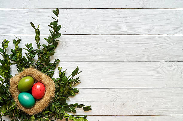 istock Nest colored eggs wreath on white wooden planks background 515223470