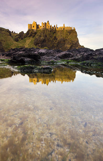 istock Dunluce Castle in early morning light, reflected in a seaside puddle. 515225901