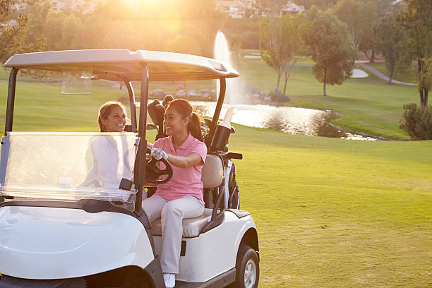 Red colored golf cart with green tree background.