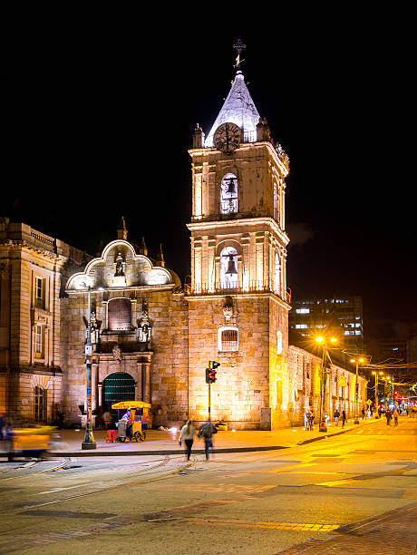 Bogota, Colombia - January 10, 2015: People walking along the streets and vendors stationed outside an illuminated Iglesias de San Francisco in Bogota, Colombia. 