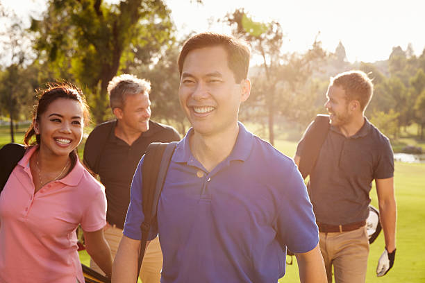 grupo de jogadores de golfe a caminhar ao longo de navegação transporte sacos de golfe - golf four people young adult playing imagens e fotografias de stock