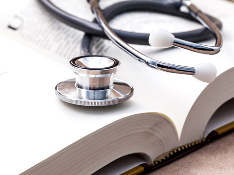 Stethoscope on a textbooks with shallow depth of field for medical college concept.