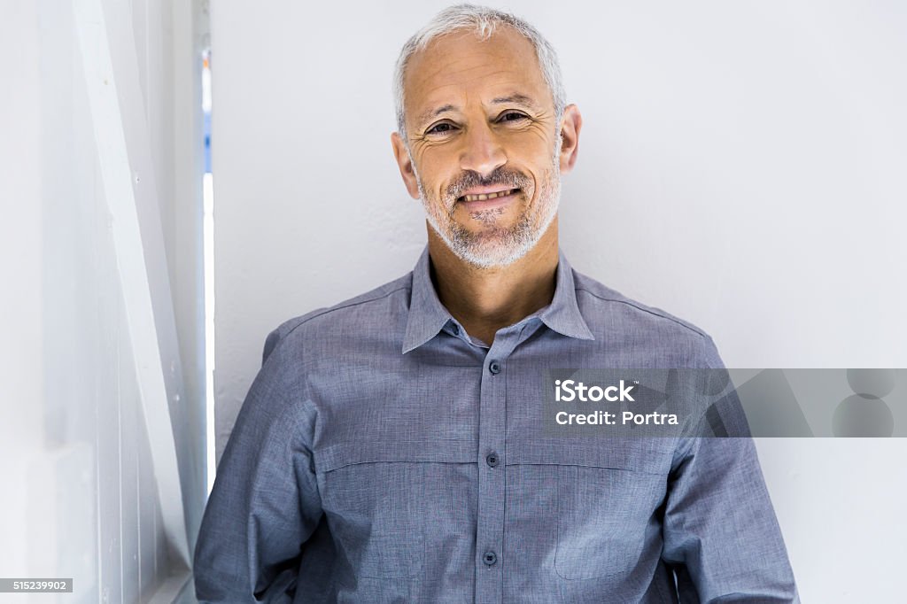 Confident businessman smiling in office A photo of confident businessman. Mature male professional is smiling. He is wearing casual shirt in office. Men Stock Photo