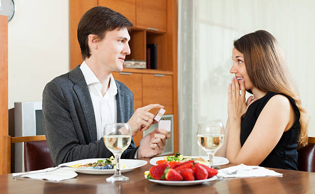 Man presents girl ring Man presenting to amazed girl  ring in box  at table in home wonderingly stock pictures, royalty-free photos & images