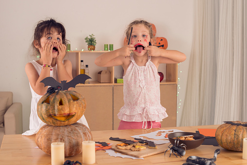 Playful girls making scary faces while preparing for the Halloween