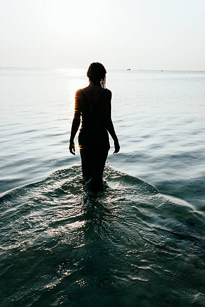 silhouette di una donna bagnata in piedi nell'oceano - camminare nellacqua foto e immagini stock