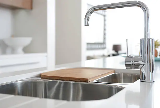 Modern stainless steel faucet and sink on kitchen,with chopping board on top of sink