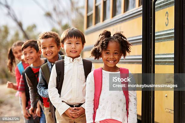 Elementary School Kids Queueing To Get On To A School Bus Stock Photo - Download Image Now