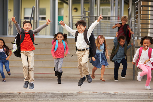 A group of energetic elementary school kids leaving school
