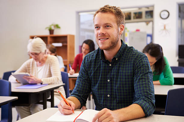 istock Young man looking up at the board at adult education class 515263322