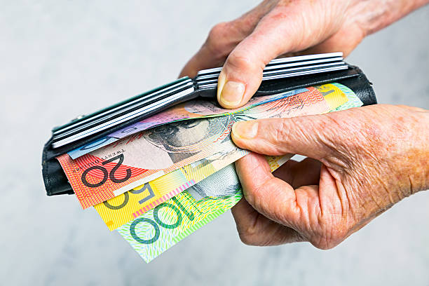 Close-up senior female hands taking Australian banknotes from purse Close-up, senior female hands taking Australian banknotes (cash, currency) from purse containing many credit cards.  Horizontal, studio, copy space. australian dollar stock pictures, royalty-free photos & images