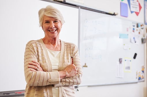 Portrait of confident senior female teacher in classroom