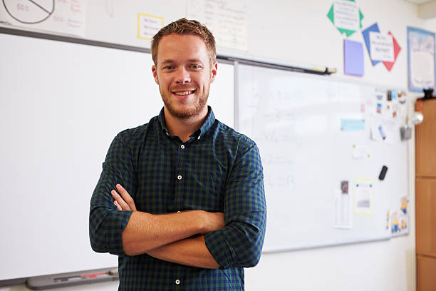 Portrait of confident Caucasian male teacher in classroom Portrait of confident Caucasian male teacher in classroom instructor stock pictures, royalty-free photos & images