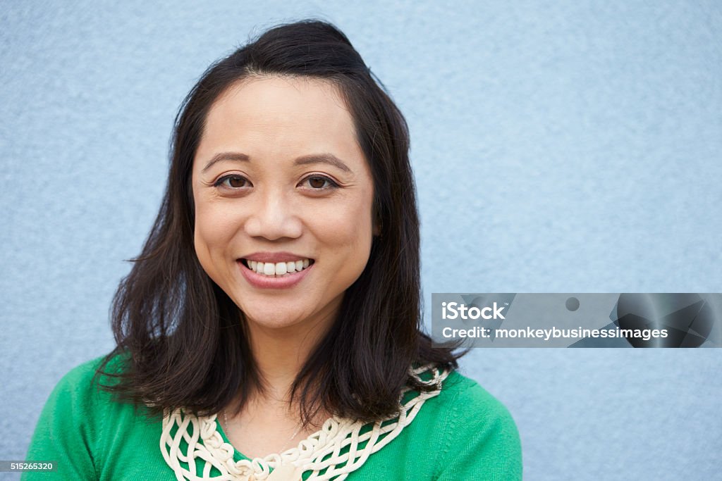 Portrait of smiling Asian woman against grey wall Asian and Indian Ethnicities Stock Photo