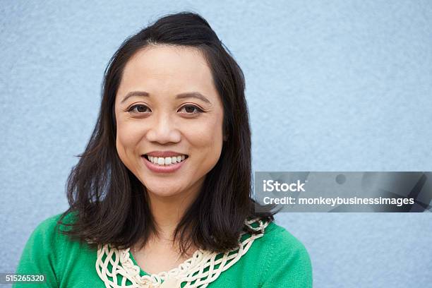 Portrait Of Smiling Asian Woman Against Grey Wall Stock Photo - Download Image Now - Asian and Indian Ethnicities, 30-39 Years, Adult