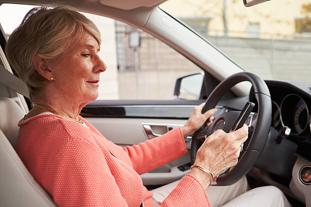 istock In car view of senior female driver using smartphone 515265820