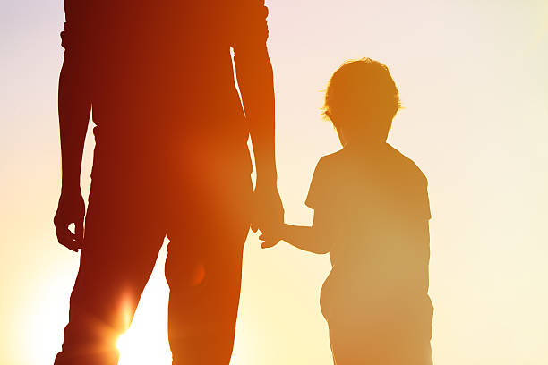 istock silhouette of father and son holding hands at sunset 515266312