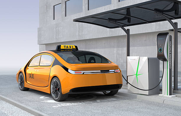 Yellow electric taxi charging in charging station stock photo