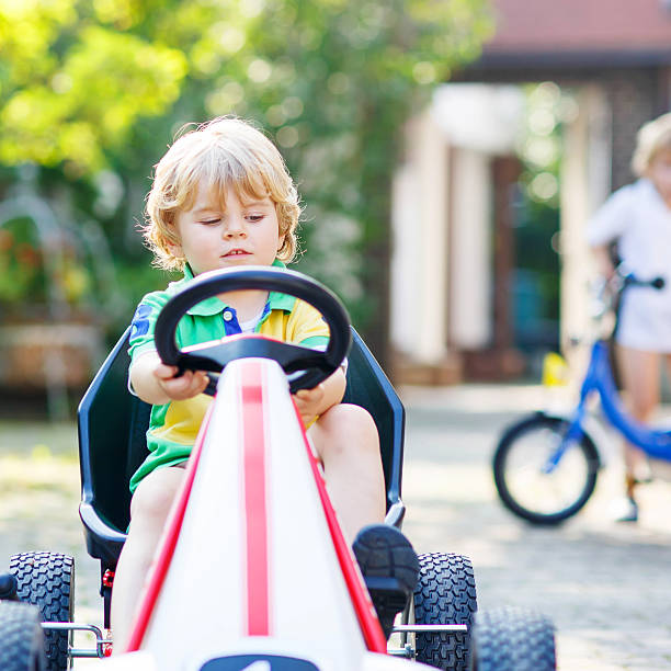 istock Active little boy driving pedal car in summer garden 515270404