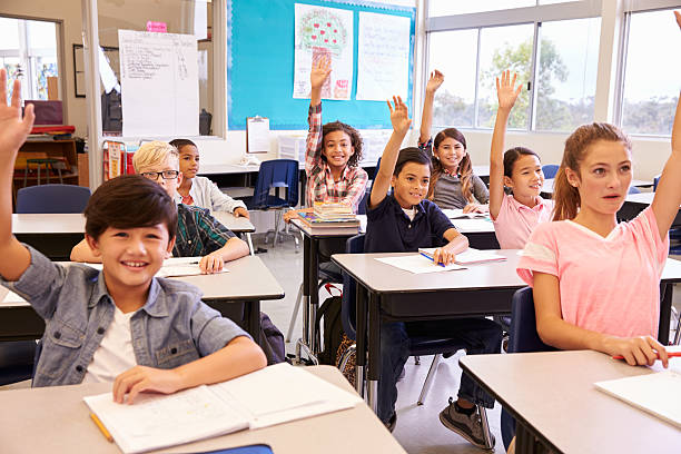 istock Elementary school kids in a classroom raising their hands 515271906