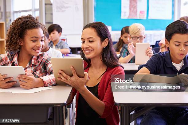 Maestro Ayudando A Niños Con Computadoras En La Escuela Primaria Foto de stock y más banco de imágenes de Maestro