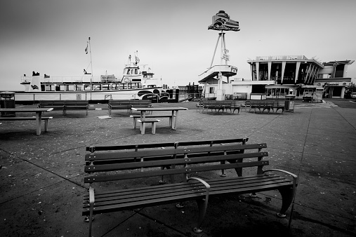 San Francisco,USA - April 14, 2014: A damp misty morning on Fisherman's Wharf with the tour and ferry boats in the background and empty desolate seats in teh foreground.  There is an eerie dawn light over the pier and the signs in teh background with some seagulls.