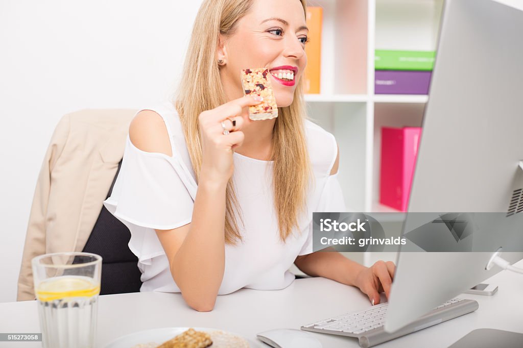 Woman having granola bar while working Breakfast Cereal Stock Photo