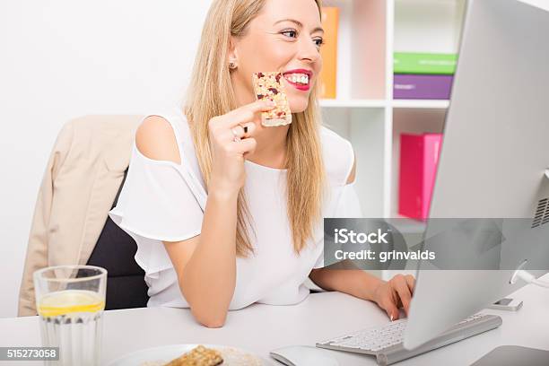 Woman Having Granola Bar While Working Stock Photo - Download Image Now - Breakfast Cereal, Computer, Women