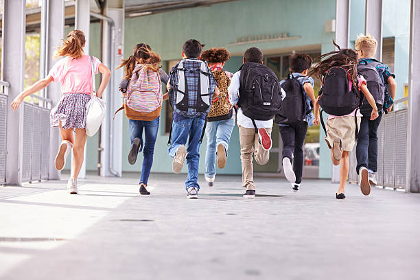 groupe d'enfants courir à l'école primaire à l'école, vue de derrière - cartable photos et images de collection