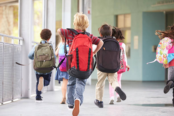 istock Group of elementary school kids running at school, back view 515273484