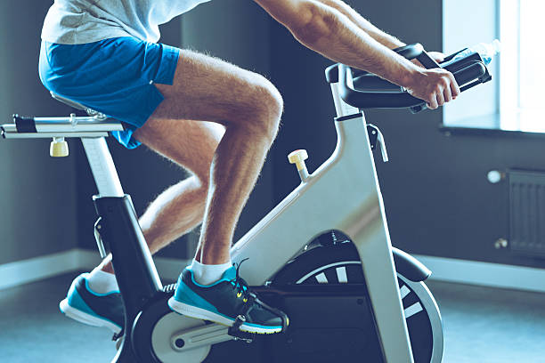 Best cardio workout. Side view part of young man in sportswear cycling at gym spin bike stock pictures, royalty-free photos & images