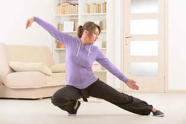 Beautiful woman doing qi gong tai chi exercise at home