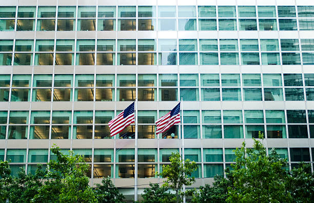 istock American Flag x 2 in front of corporate building daytime 515274113