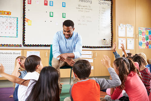 istock Elementary school kids sitting around teacher in a classroom 515274320