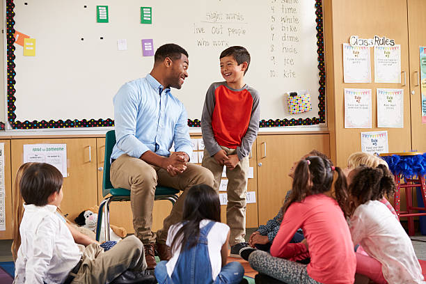 istock Schoolboy at front of elementary class talking with teacher 515274512