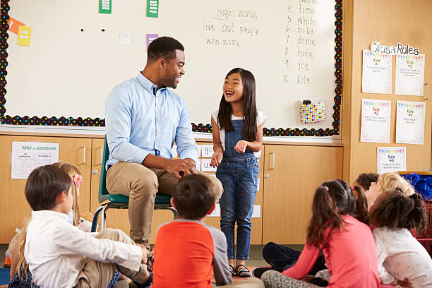 istock Schoolgirl at front of elementary class talking with teacher 515274616
