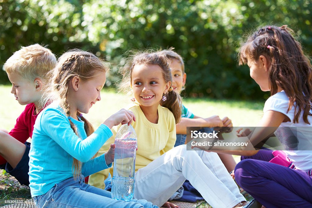 Circle of friends Portrait of happy friends chatting with each other in park Bottle Stock Photo