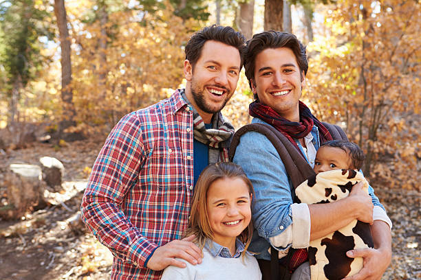 гей мужской пара с детьми, ходить через осенний лес - natural phenomenon affectionate looking at camera outdoors стоковые фото и изображения