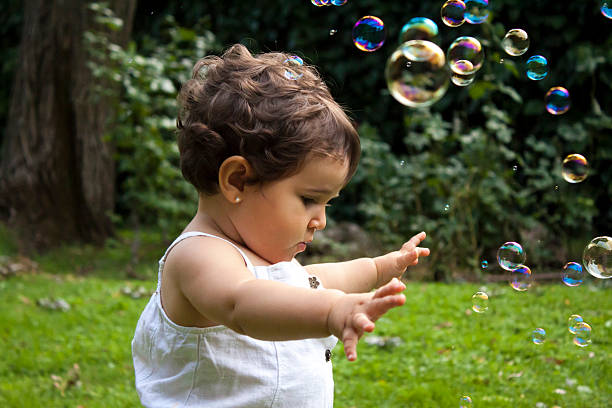 Girl playing with soap bubbles in the garden stock photo